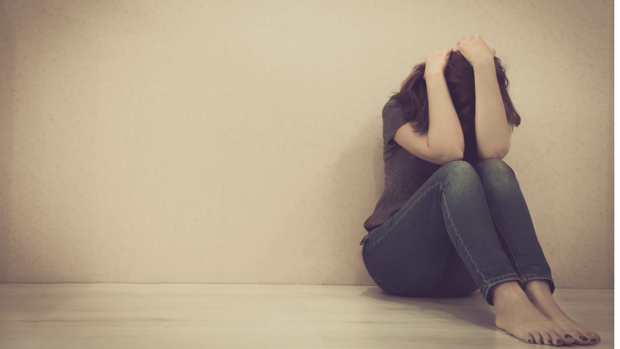 sad woman hug her knee and cry. The depression woman sit on the floor. Teenager girl with depression sitting alone on the floor in the dark room. Toned photo
